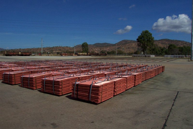 Bundles of copper cathodes stacked in a yard, ready for transport